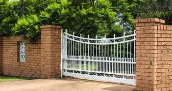 White wrought iron driveway entrance gates in brick fence